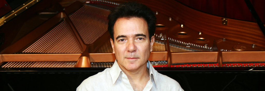 O pianista Luciano Alves com piano ao fundo.